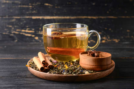 Tasty fruit tea with cinnamon and anise in cup on dark wooden backgroundの写真素材