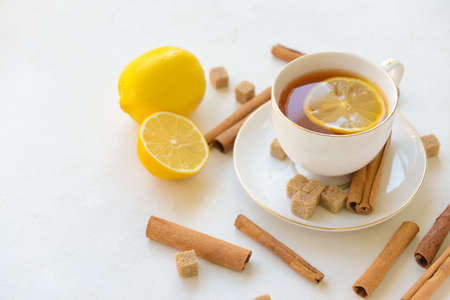Tasty tea with cinnamon and lemon in cup on light backgroundの写真素材
