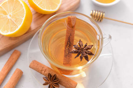 Tasty tea with cinnamon, honey and lemon in cup on light backgroundの写真素材