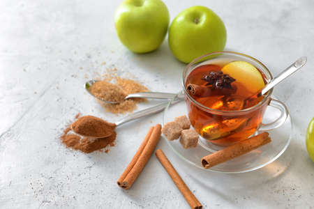Tasty apple drink with cinnamon and anise in cup on light backgroundの写真素材