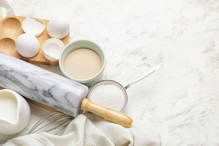 Ingredients for dough and rolling pin on light background
