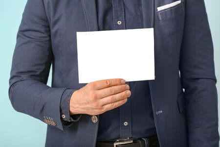 Man with blank paper sheet on light backgroundの写真素材