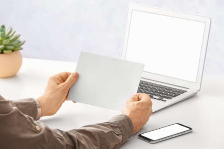Man with blank paper sheet at table in officeの写真素材