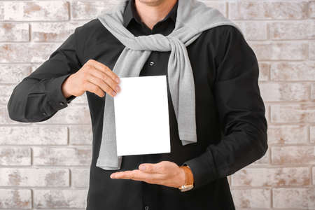 Man with blank paper sheet on brick background
