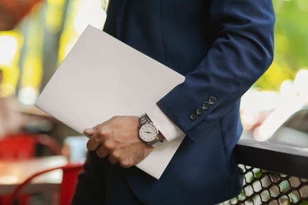 Young businessman with blank magazine outdoors