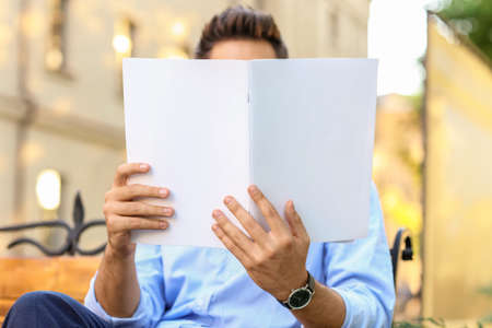 Young man reading magazine outdoors