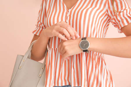 Woman with wristwatch on color background, closeup