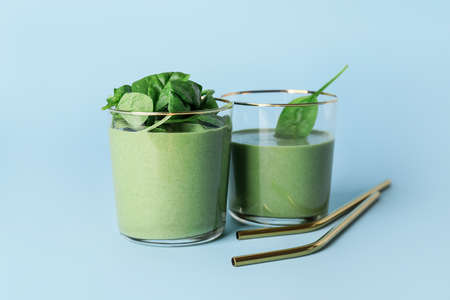 Glasses of healthy spinach smoothie on color background