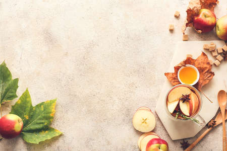 Tasty drink with spices and apple slices in cup on light backgroundの写真素材