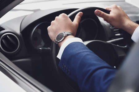 Handsome businessman with stylish wristwatch driving carの写真素材
