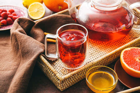 Cup of hot tea with raspberry on wicker trayの写真素材