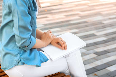 Young woman reading blank magazine in parkの写真素材