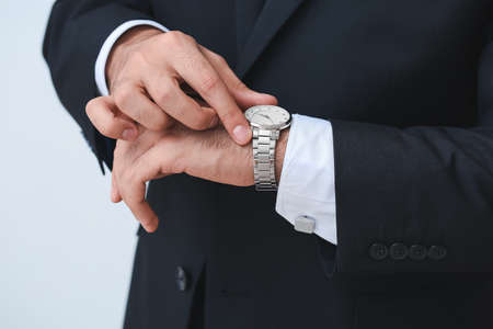 Young businessman with stylish wristwatch on light backgroundの写真素材