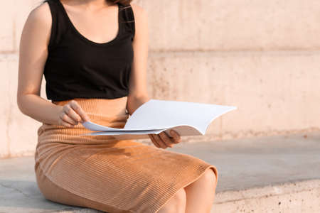 Young woman reading blank magazine outdoorsの写真素材