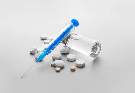 Syringe with ampoule and pills on light backgroundの写真素材