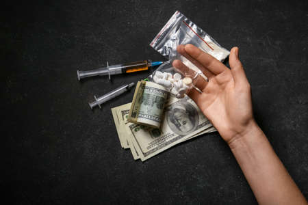 Male hand with drugs and money on dark backgroundの写真素材
