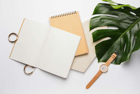 Stylish wristwatch, blank notebook and earrings on light backgroundの写真素材