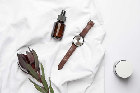 Stylish wristwatch, flower and cosmetic bottles on light backgroundの写真素材