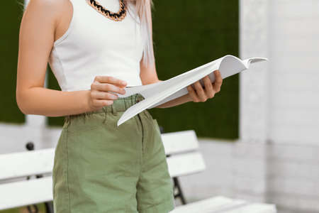 Beautiful woman reading blank magazine outdoors