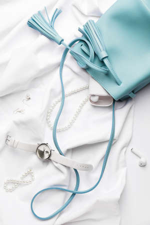 Stylish wristwatch, jewelry and earphones on light backgroundの写真素材