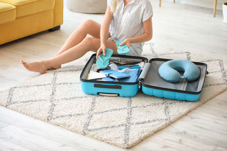 Young woman packing suitcase at home. Travel concept