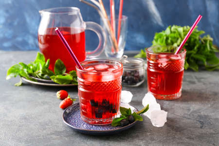 Jug and glasses of tasty cold tea on dark background