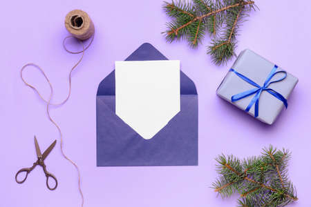 Beautiful Christmas gift with empty card and envelope on color background