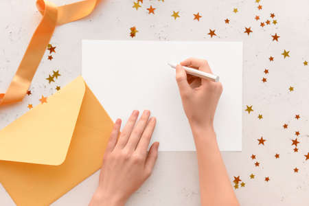 Female hands with blank card, envelope and Christmas confetti on white backgroundの写真素材