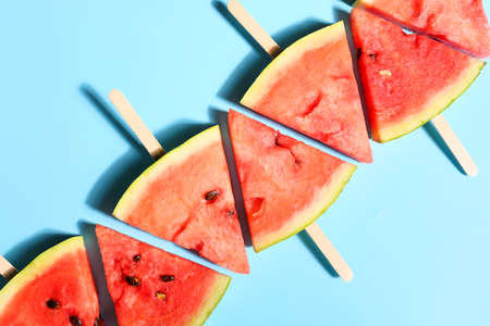 Slices of ripe watermelon with wooden sticks on color backgroundの写真素材