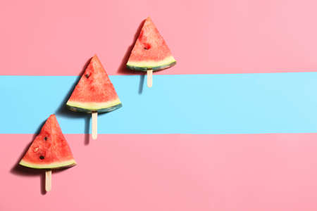 Slices of ripe watermelon with wooden sticks on color backgroundの写真素材