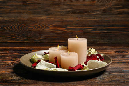 Tray with burning candles and flower petals for celebration of Divaly on wooden backgroundの写真素材