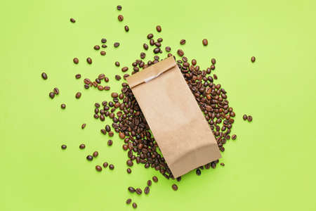 Paper bag with coffee beans on color background
