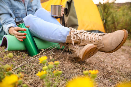 Young female tourist sitting near tent in countrysideの写真素材