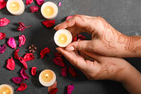 Female hands with burning candles and flower petals for celebration of Divaly on dark backgroundの写真素材
