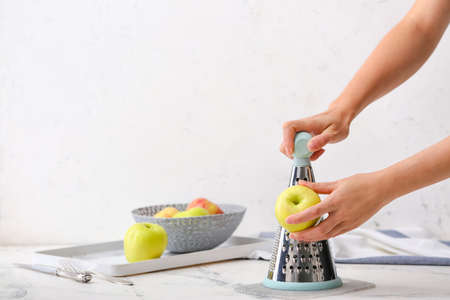 Woman grating apples at table