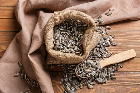 Bag and spoon with sunflower seeds on wooden background