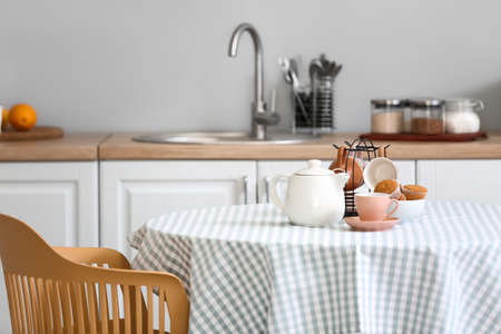 Teapot, cups and muffins on table in kitchenの写真素材