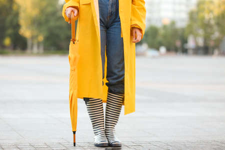 Beautiful young woman with umbrella wearing raincoat outdoorsの写真素材