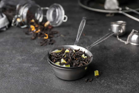 Tea strainer with dry leaves on dark background