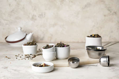 Composition with bowls of dry fruit tea on light background