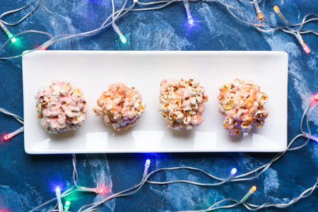 Plate with tasty popcorn balls on color background