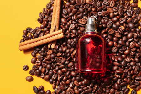 Bottle of perfume with coffee beans on color backgroundの写真素材