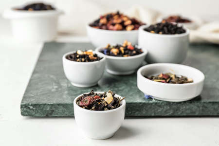 Bowls with different types of dry fruit tea on light backgroundの写真素材