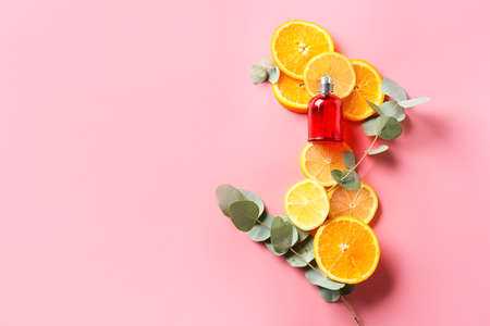 Bottle of perfume with citrus fruits on color backgroundの写真素材