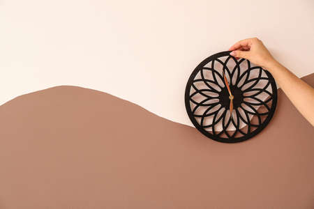 Female hand with clock on color wall