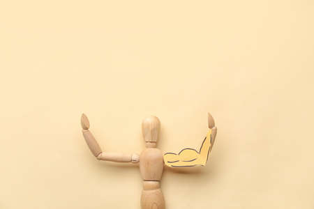 Wooden mannequin with drawn muscular arm on color backgroundの写真素材