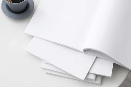 Blank magazines and cup of coffee on table