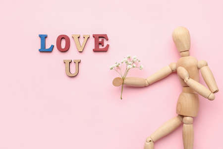 Wooden mannequin with flowers and words LOVE U on color backgroundの写真素材