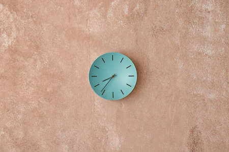 Stylish clock hanging on color wall