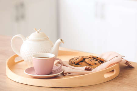 Tray with teapot, cup and cookies on kitchen tableの写真素材